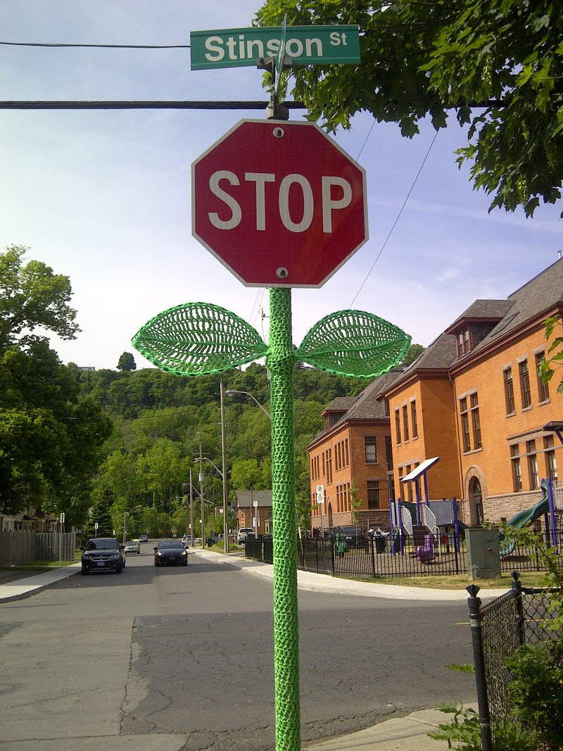 A stop sign on Stinson Street is wrapped in green crocheted stem and leaves.