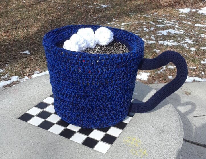 A large crocheted blue mug with crocheted marshmallows.